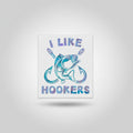 Hand holding a sticker with 'I Like Hookers' design on a kitchen floor.